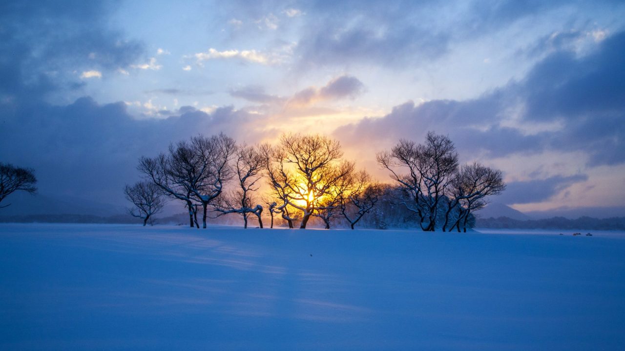 真冬の裏磐梯桧原湖　雪の積もった湖面の向こうに陽が昇る